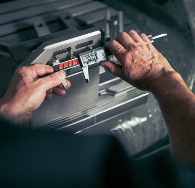 Zerspanungsmechaniker misst eine Metallkomponente